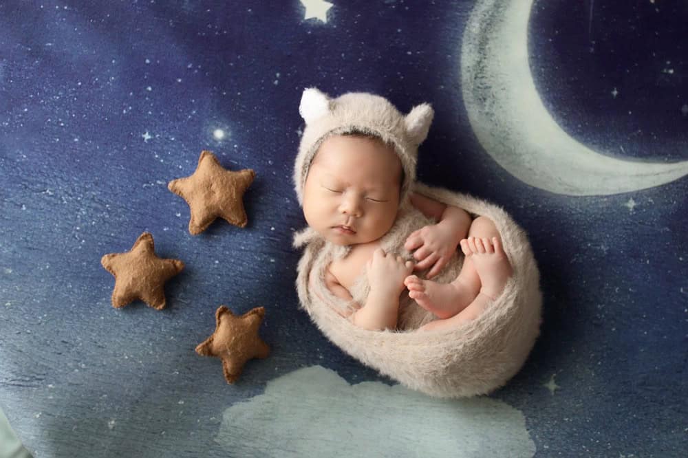Sleeping baby with stars and night sky blanket behind them